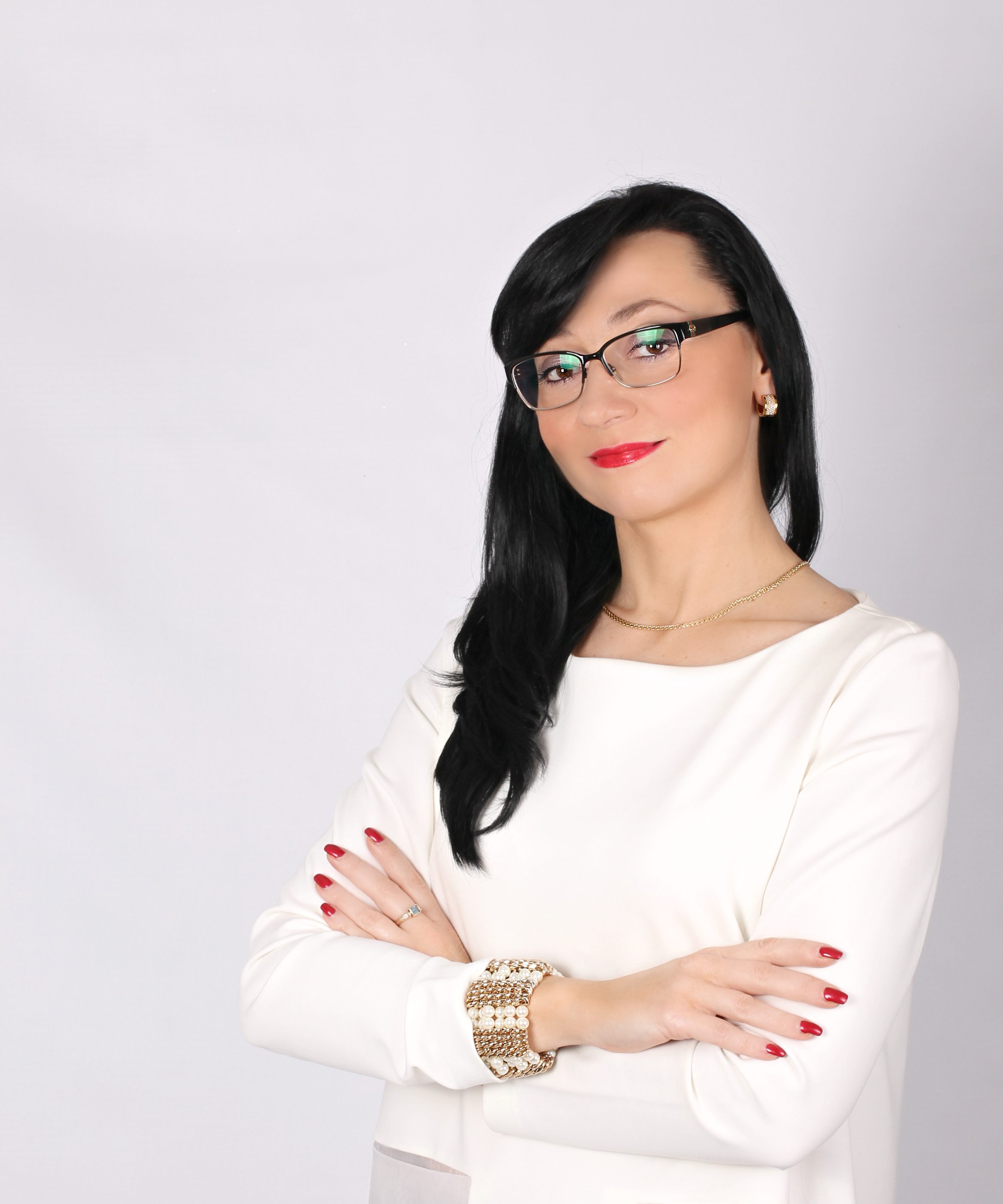 A woman in glasses posing with her arms crossed.